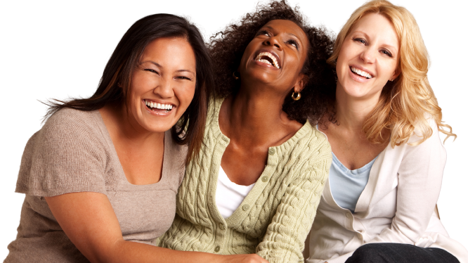 Three women of different races smiling and embracing one another